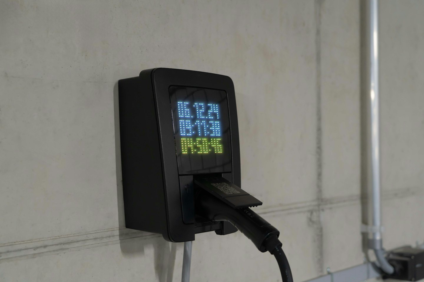 Schwarze Ladestation für Elektroautos an einer Betonwand.
