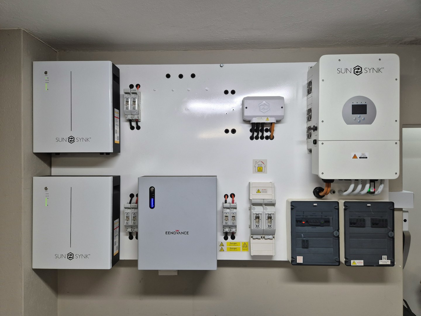 Heimenergiesystem mit Batterien und Wechselrichtern an einer weißen Wand.